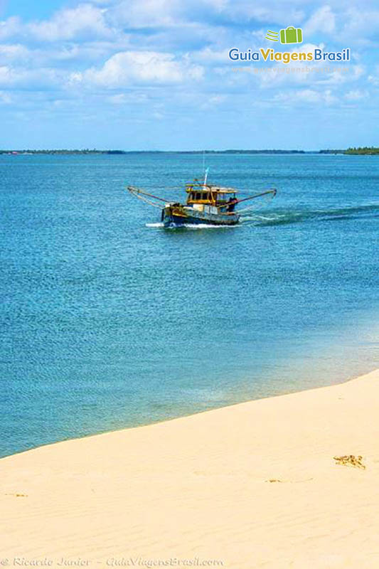 Imagem da praia de Foz Rio São Francisco e no mar um barco passando compondo a bela paisagem, em Alagoas, Brasil. 