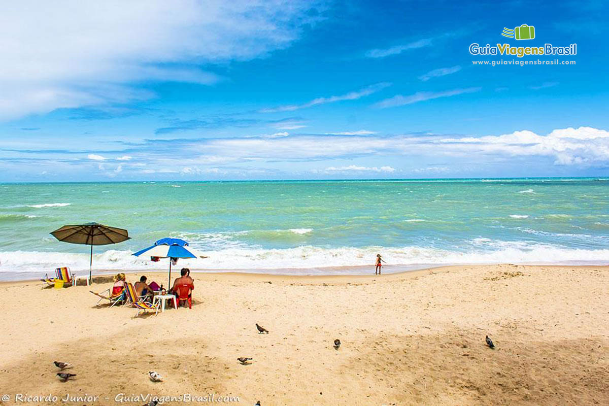 Imagem de turistas e criança aproveitando um belo dia de sol na Praia de Jatiúca, em Maceió, Alagoas, Brasil.