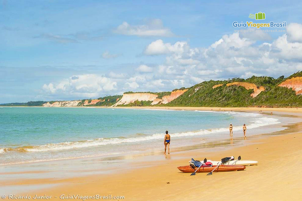 Imagem de dois caiaque na areia e pessoas caminhando na Praia da Pitinga.