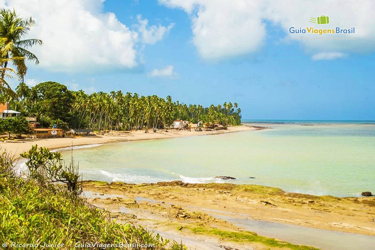 Imagem da Praia da Bitingui e ao fundo algumas casa e quiosques.