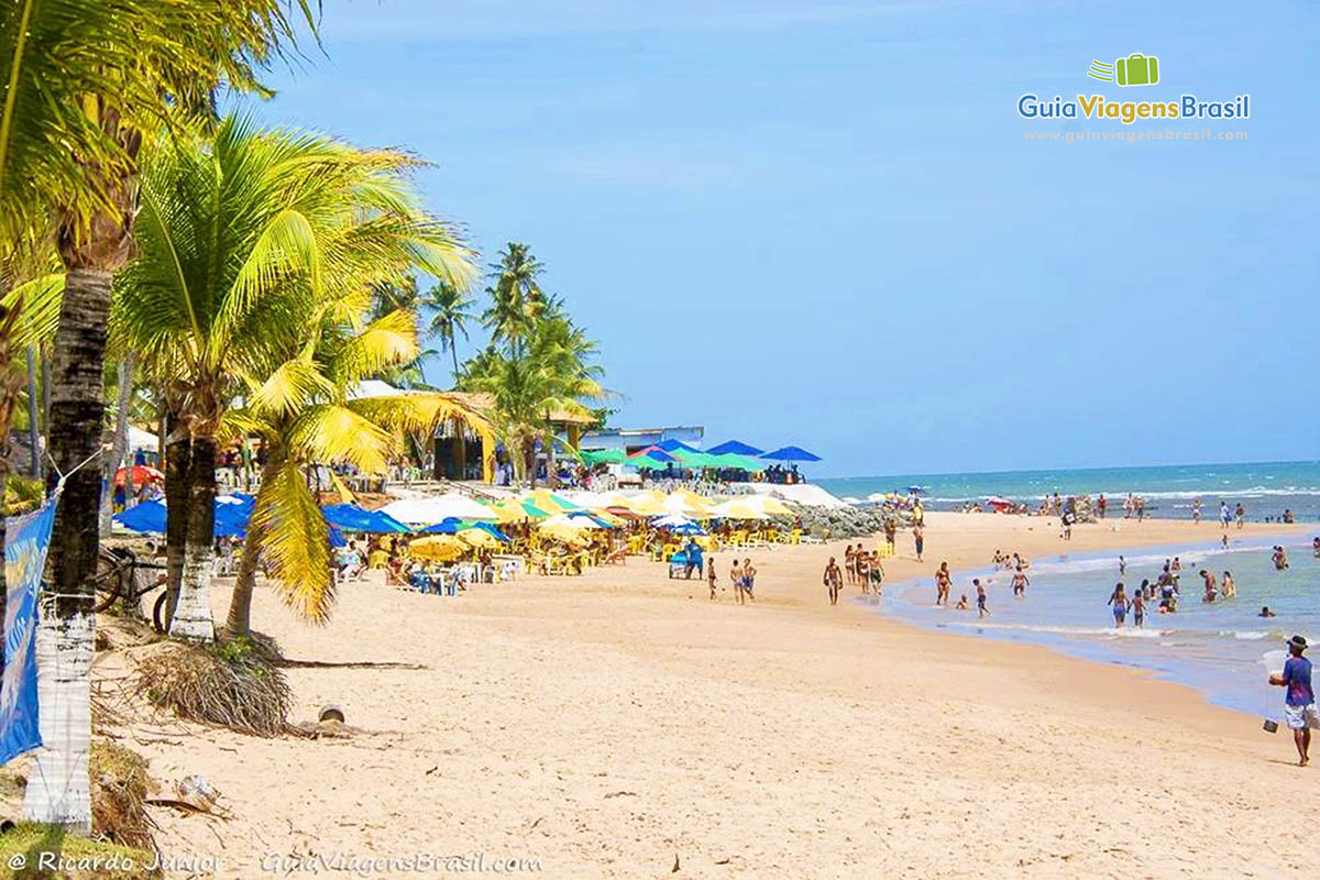 Imagem de turistas com criança na praia.