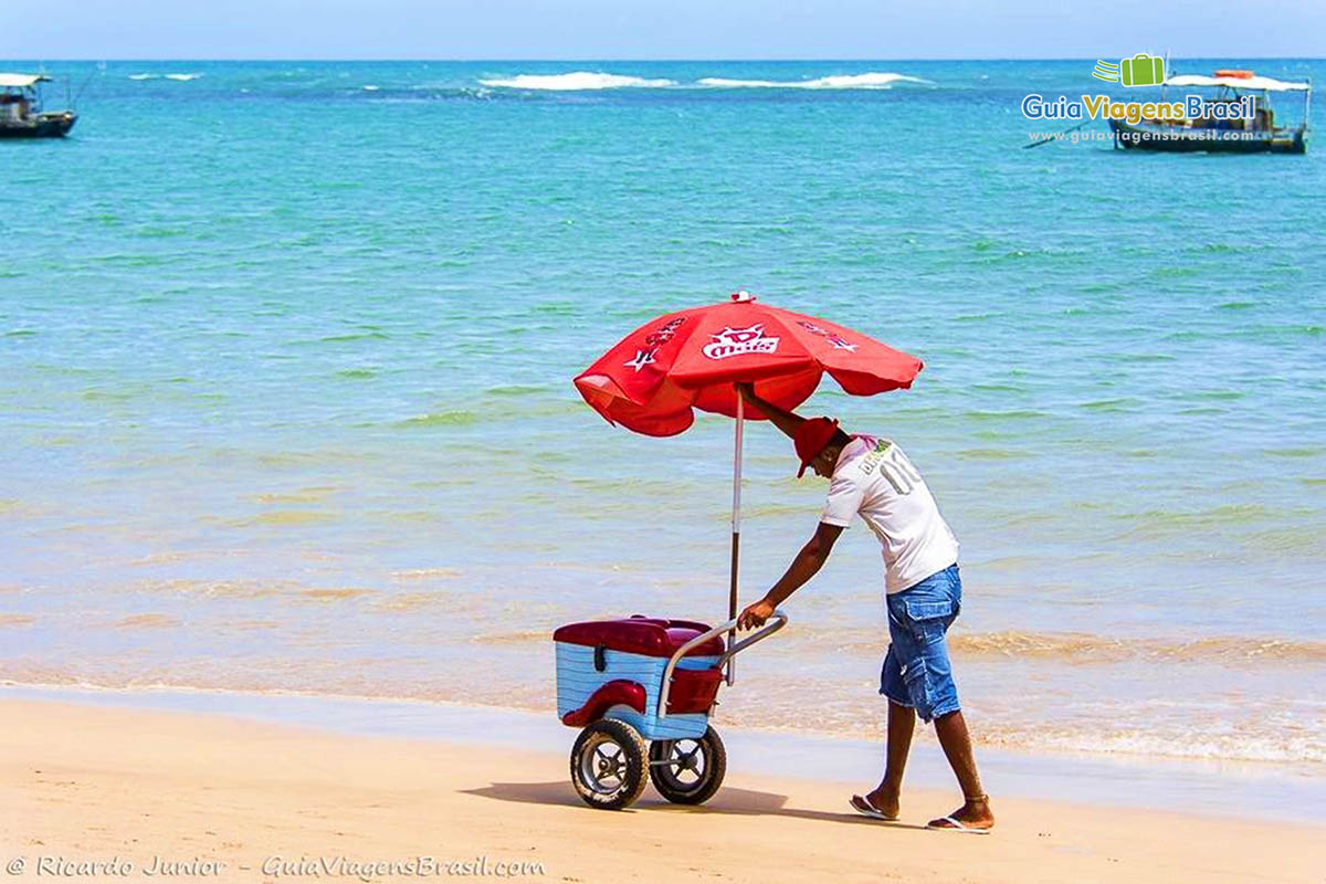 Imagem de um vendedor de sorvete andando pela praia.