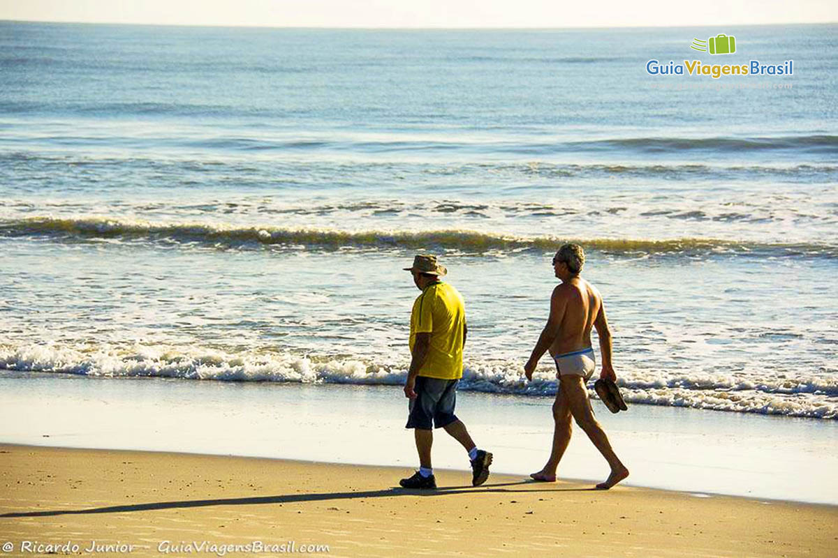 Imagem fim de tarde na Praia de Itapoá ideal para prática de exercício, dois amigos caminhando, em Itapoá, Santa Catarina, Brasil.