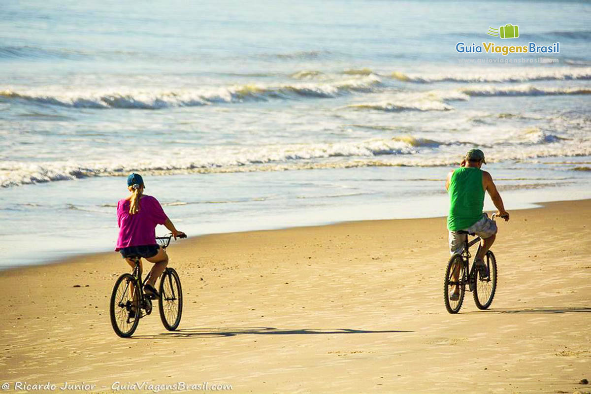 Imagem de um casal andando de bicicleta na Praia de Itapoá, em Itapoá, Santa Catarina, Brasil.