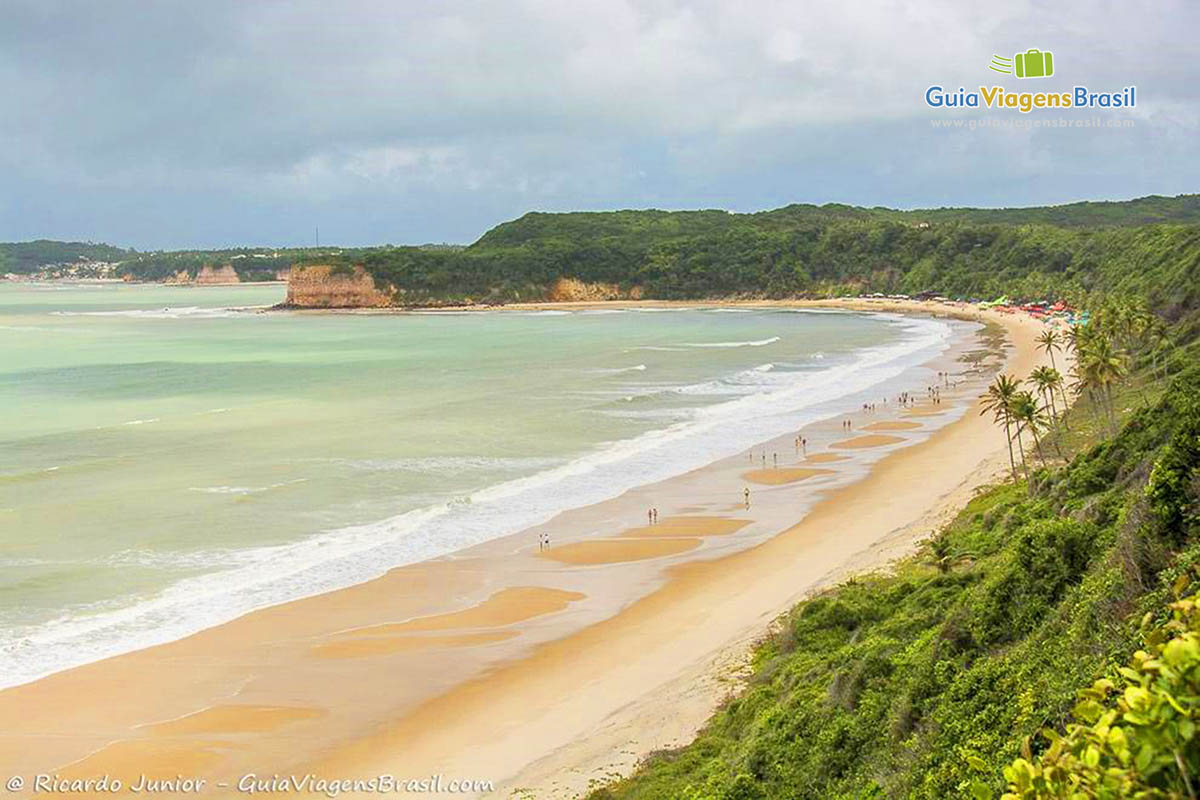 Imagem do alto com vista para praia e turistas aproveitando um belo dia.