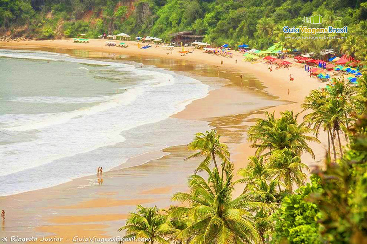 Imagem da encantadora Praia do Madeiro, com guarda sol para os turistas.