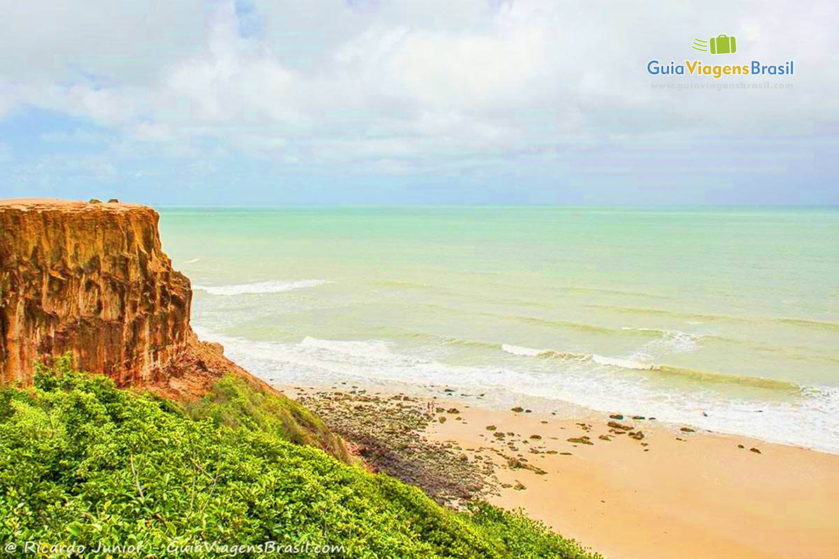 Imagem das rochas e vegetação na Praia do Madeiro.