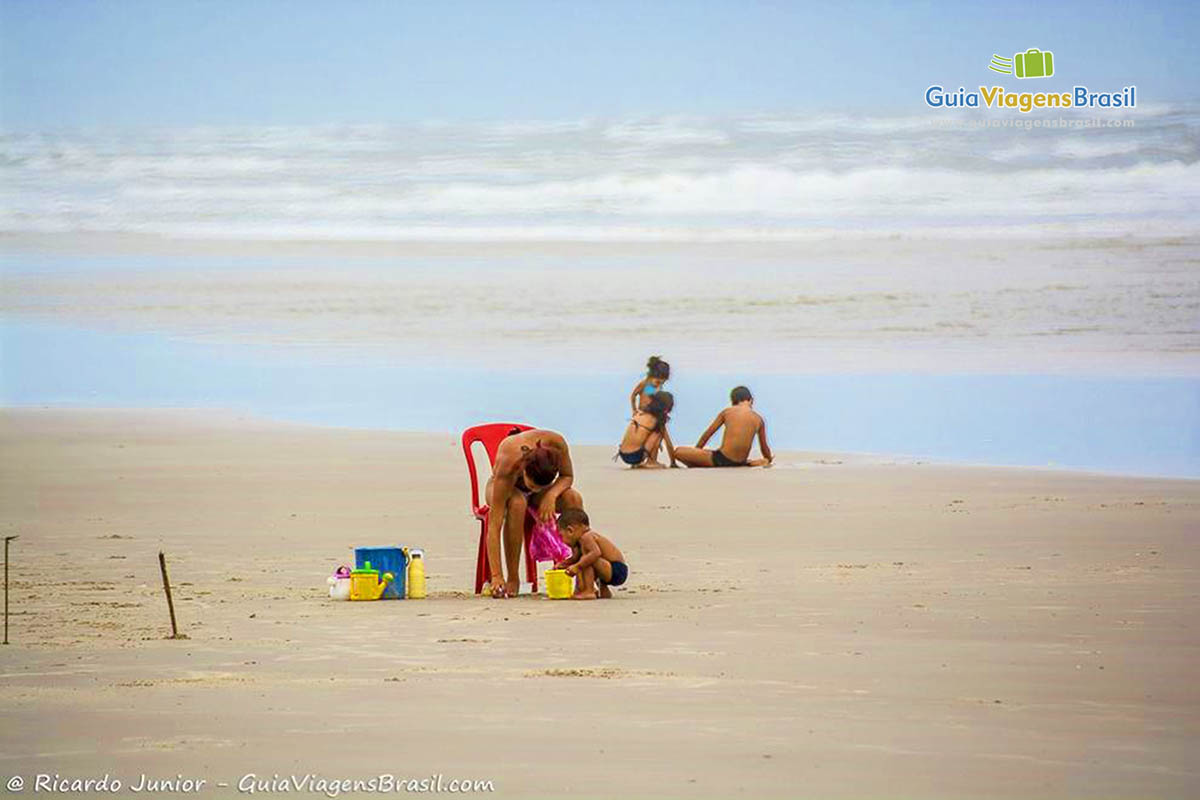 Imagem de mãe brincando com filho na areia da Praia de Mangue Seco.