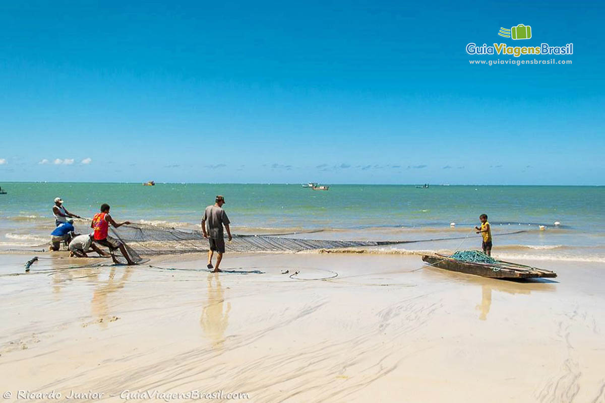 Imagem de vários pescadores puxando rede de pesca em Maragogi.