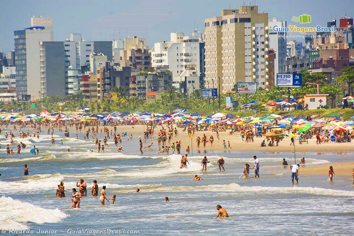Imagem de vários turistas aproveitando a Praia de Matinhos, em Santa Catarina, Brasil.