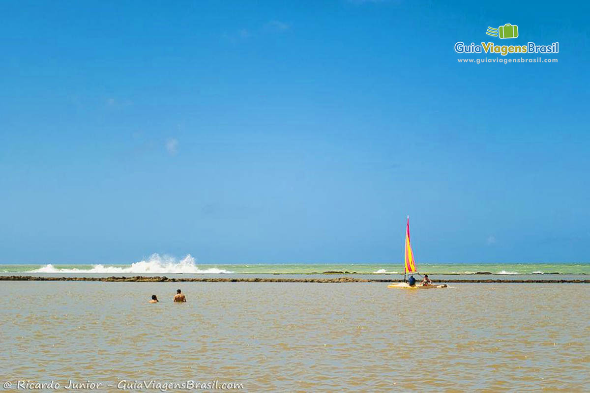 Imagem de turistas nadando nas águas da Praia de Muro Alto, em Porto de Galinhas.