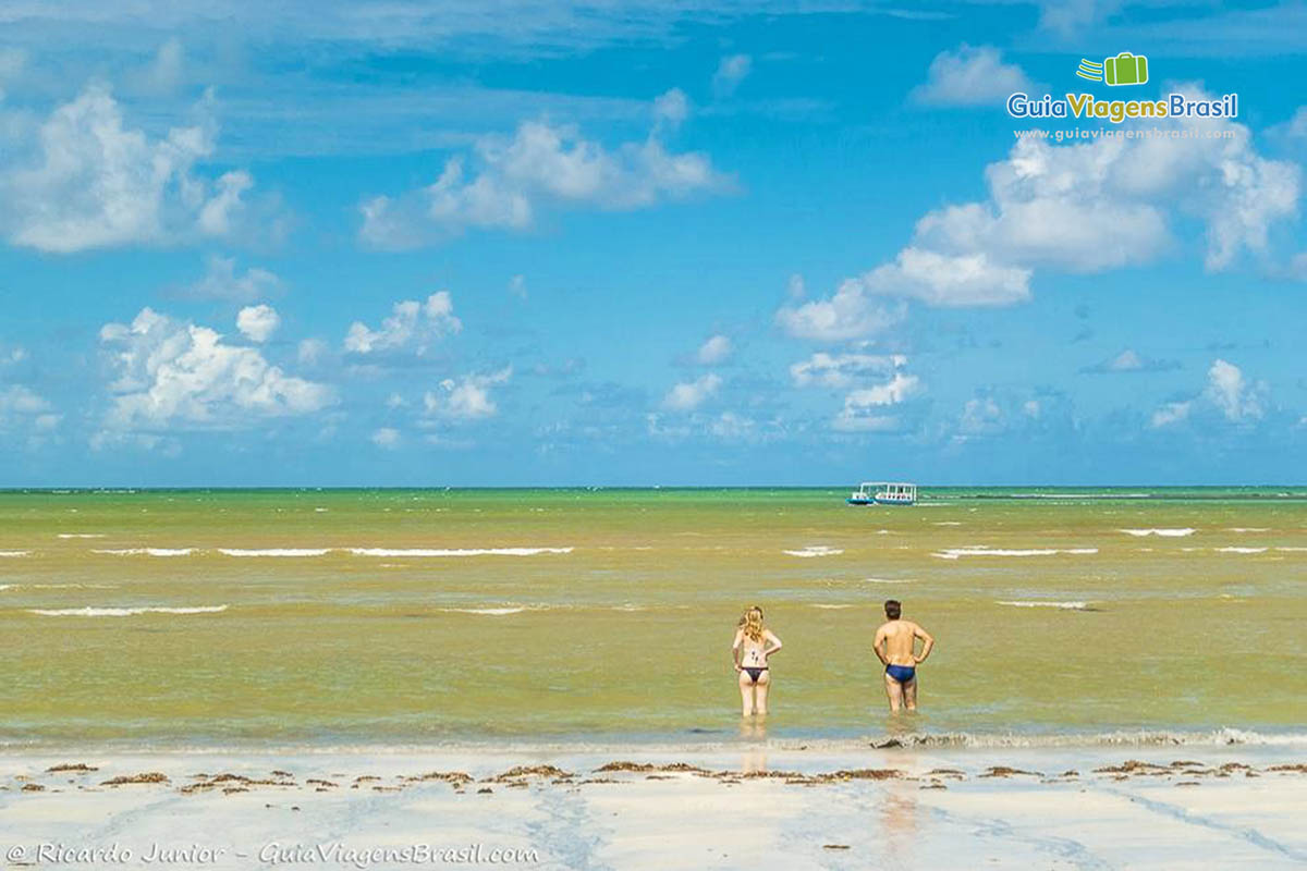 Imagem de casal na beira do mar  na praia.