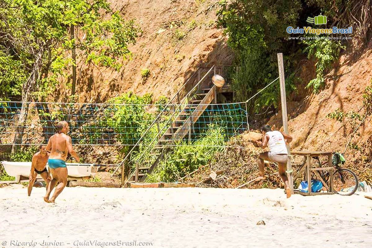 Imagem de turistas se exercitando jogando futevôlei.