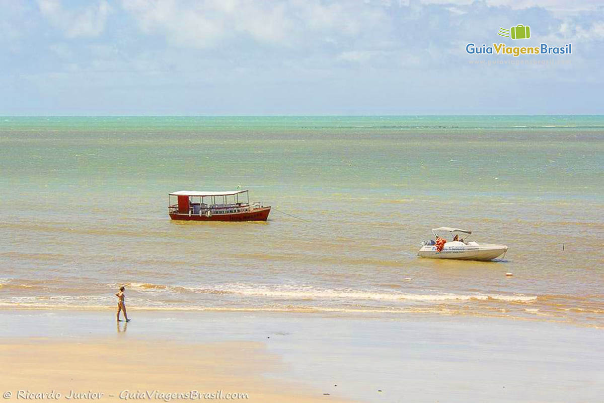 Imagem de um barco de passeio e uma lancha nas águas da Praia de Pirangi.