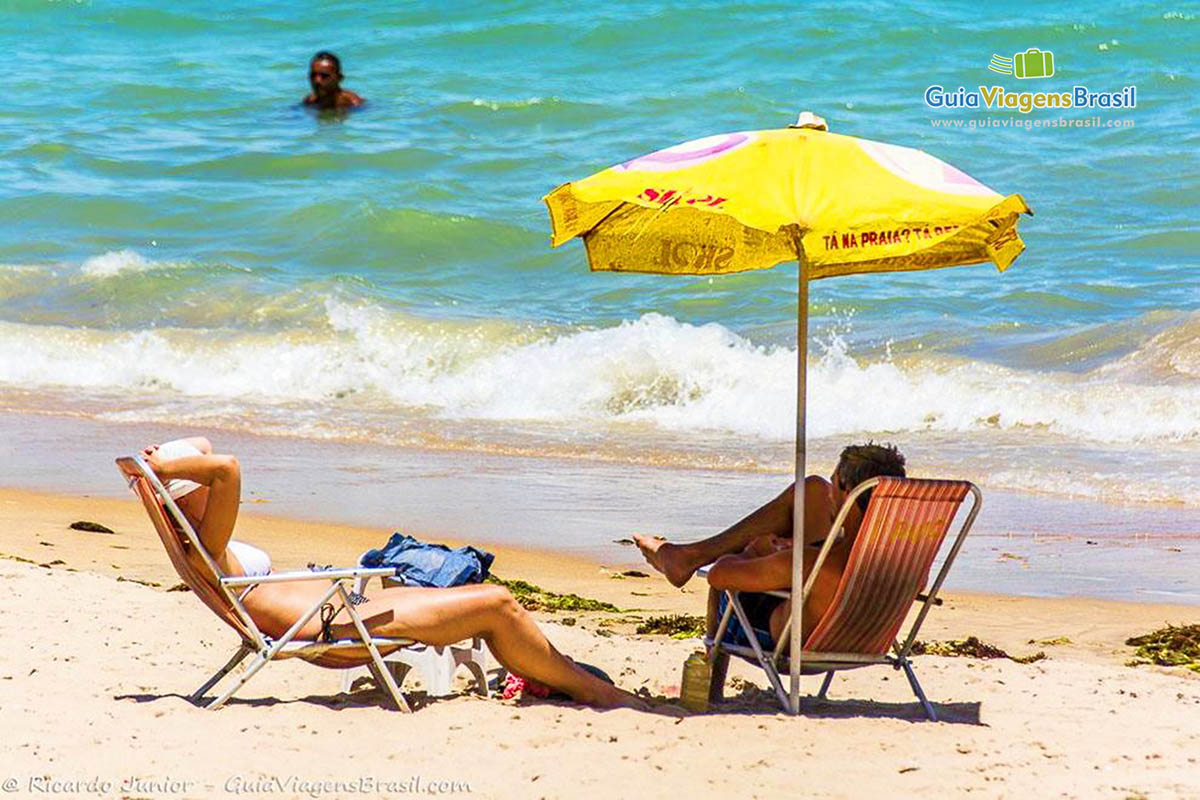Imagem de casal tomando sol e a beira mar na Praia de Ponta Verde, em Maceió, Alagoas, Brasil.