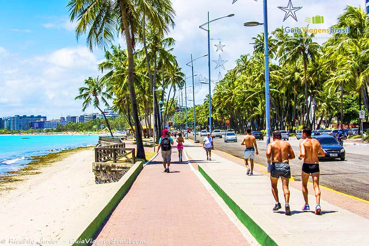 Imagem de pessoas caminhando no calçadão da Praia de Ponta Verde em Maceió, Alagoas, Brasil.
