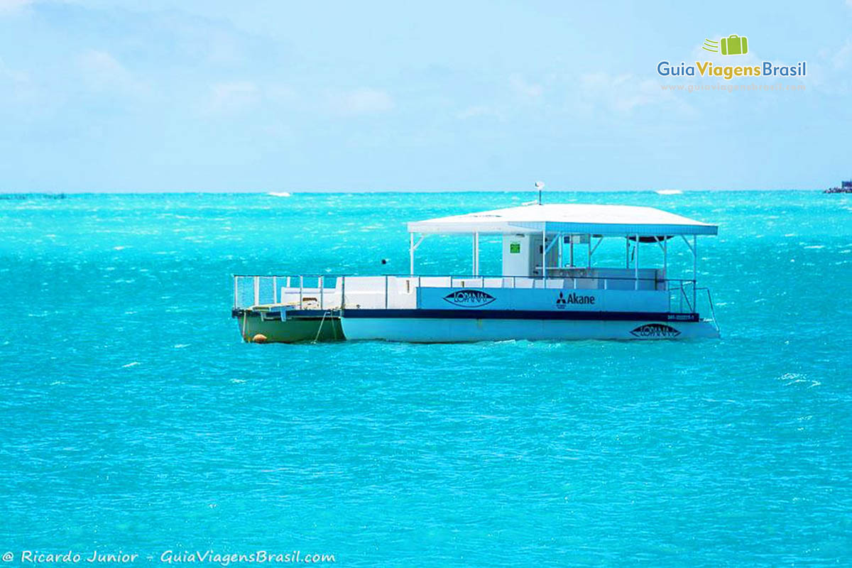 Imagem de barco no alto mar nas águas azuis da Praia de Ponta Verde, em Maceió, Alagoas, Brasil.