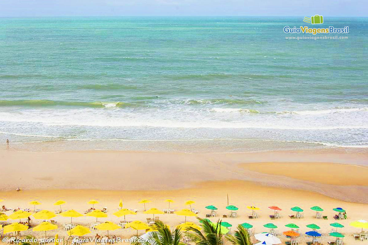 Imagem de vários guarda sol e do mar da Praia do Amor.