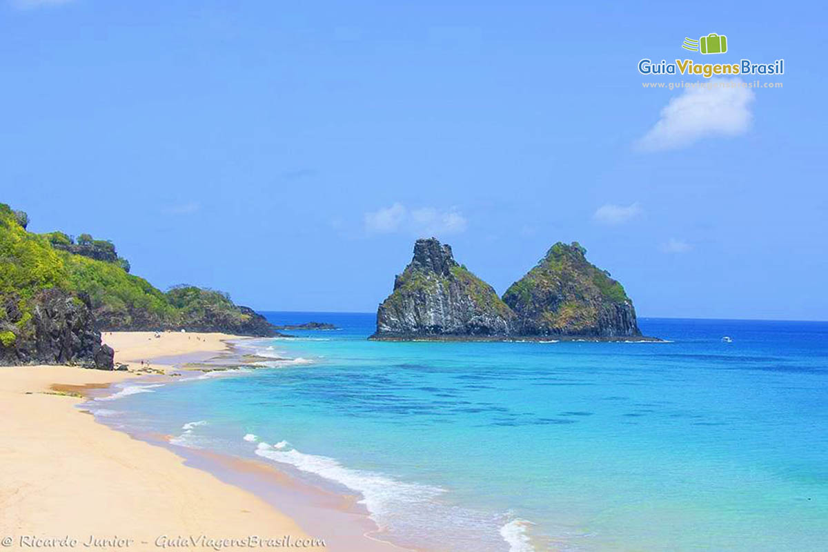 Imagem da praia com o mar azul turquesa e Morro Dois Irmãos no fundo, na Praia do Bode, em Fernando de Noronha, Pernambuco, Brasil.