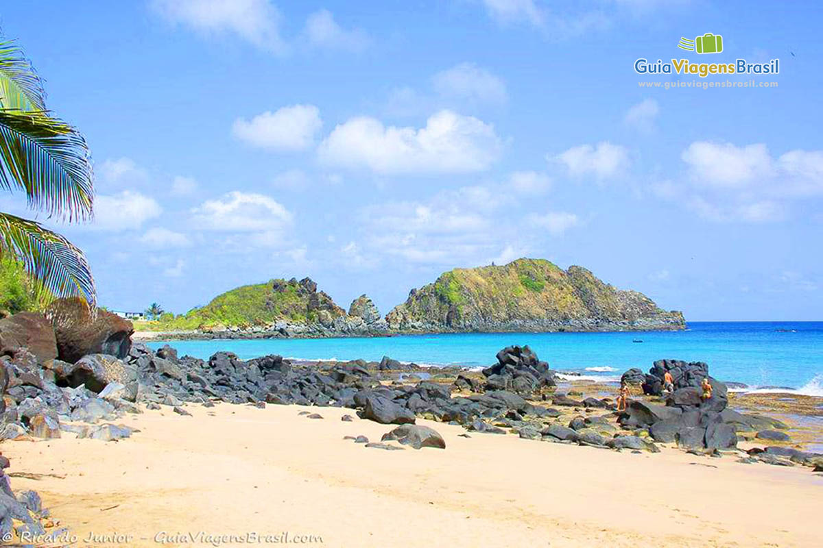 Imagem das areias e ao fundo duas grandes pedras na Praia do Cachorro, em Fernando de Noronha, Pernambuco, Brasil.