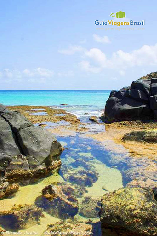 Imagem das águas transparentes sob as pedras da Praia do Cachorro, em Fernando de Noronha, Pernambuco, Brasil.