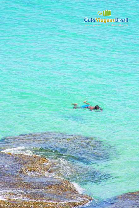 Imagem de criança mergulhando na Praia do Cachorro, em Fernando de Noronha, Pernambuco, Brasil.