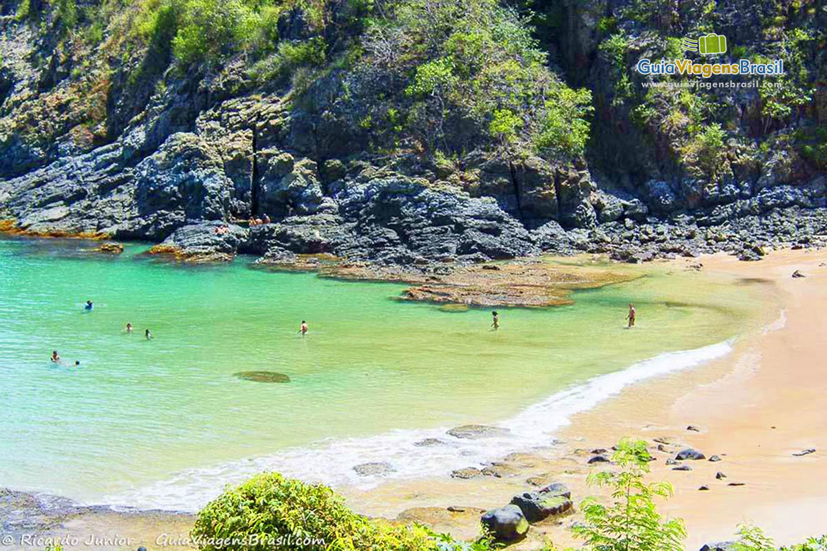 Imagem de turistas nas águas claras da Praia do Cachorro, em Fernando de Noronha, Pernambuco, Brasil.