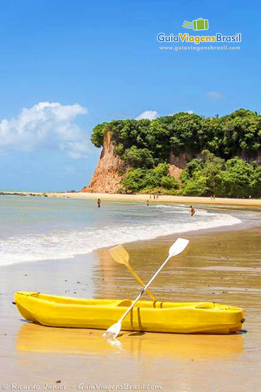 Imagem de caiaque amarelo na areia da praia.