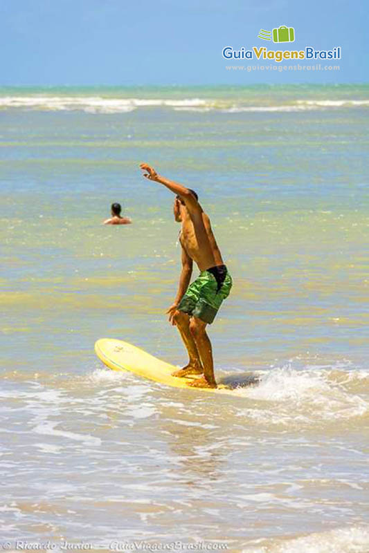 Imagem do surfista em cima da prancha.