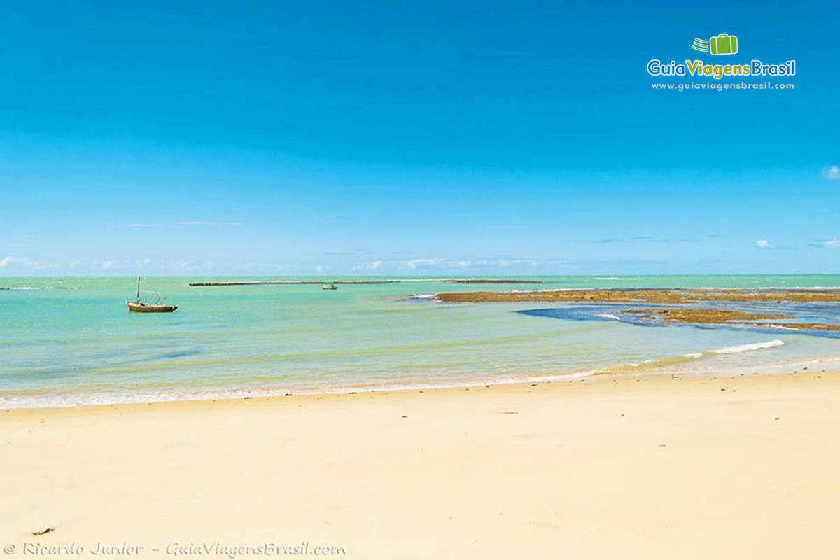 Imagem do Praia do Espelho com um barco de pescador nas águas azuis da praia.