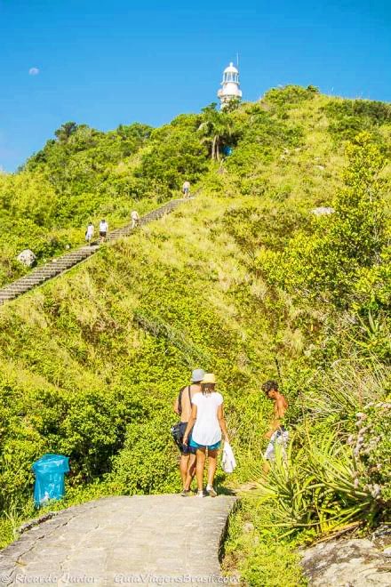 Imagem de turistas subindo as escadas para chegar no Farol, da Praia do Farol, na Ilha do Mel, Paraná, Brasil.