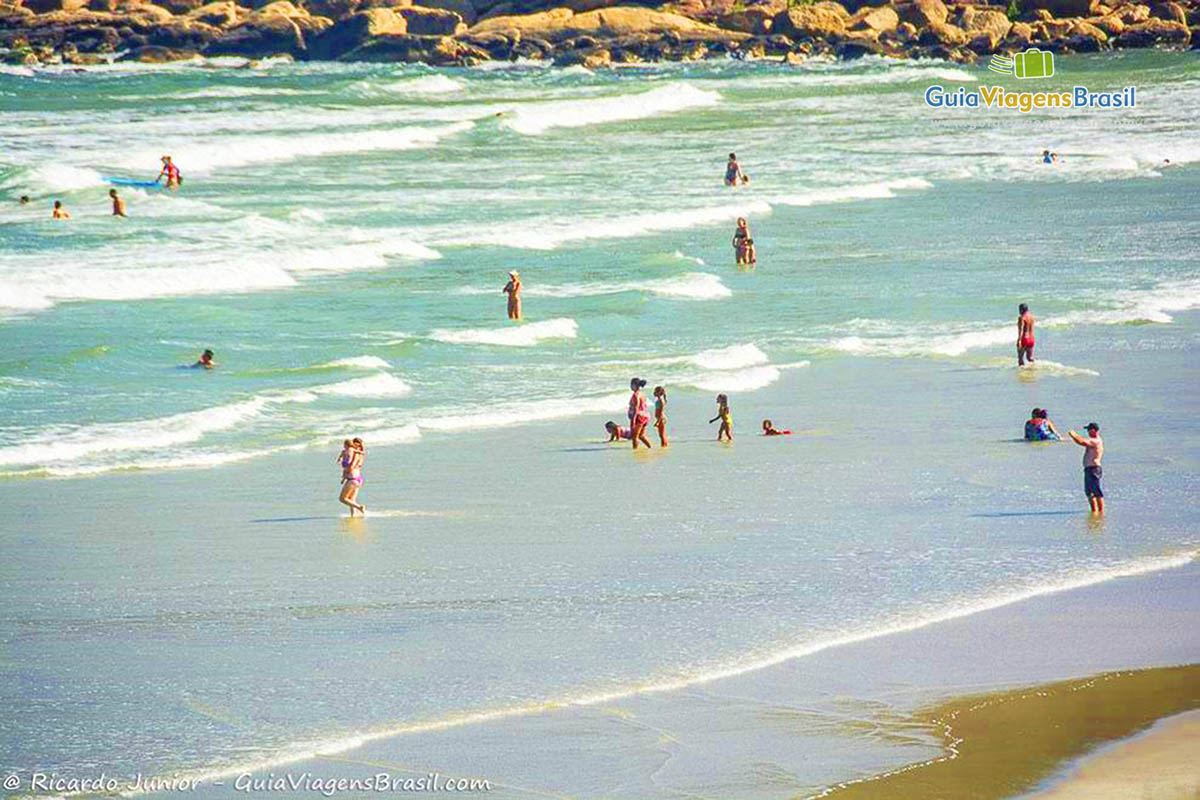 Imagem de crianças nas pequenas ondas da Praia do Farol, Ilha do Mel, Paraná, Brasil.