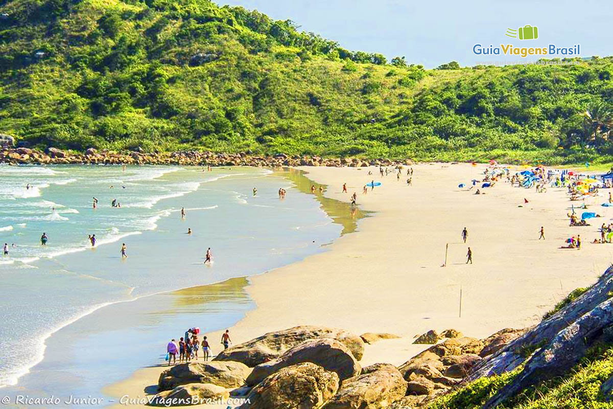 Imagem de turistas chegando na Praia do Farol e outros já aproveitando o mar e o sol, na Ilha do Mel, Paraná, Brasil.