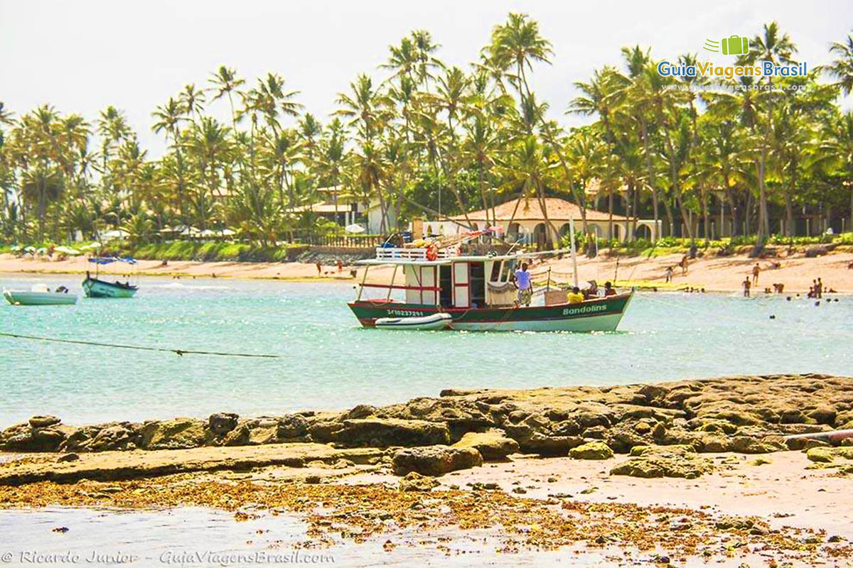 Imagem dos arecifes e atrás barco de pescador nas águas da Praia do Forte.