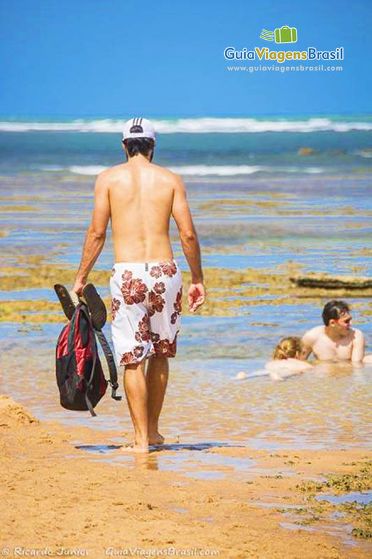 Imagem de turista andando na piscina natural.