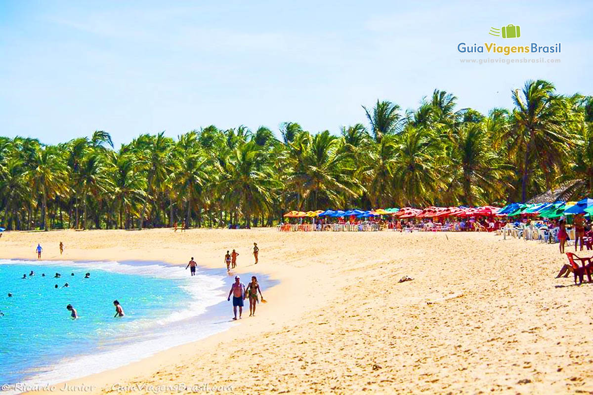 Imagem de crianças na água e casal caminhando na beira da Praia do Gunga, em Maceió, Alagoas, Brasil.