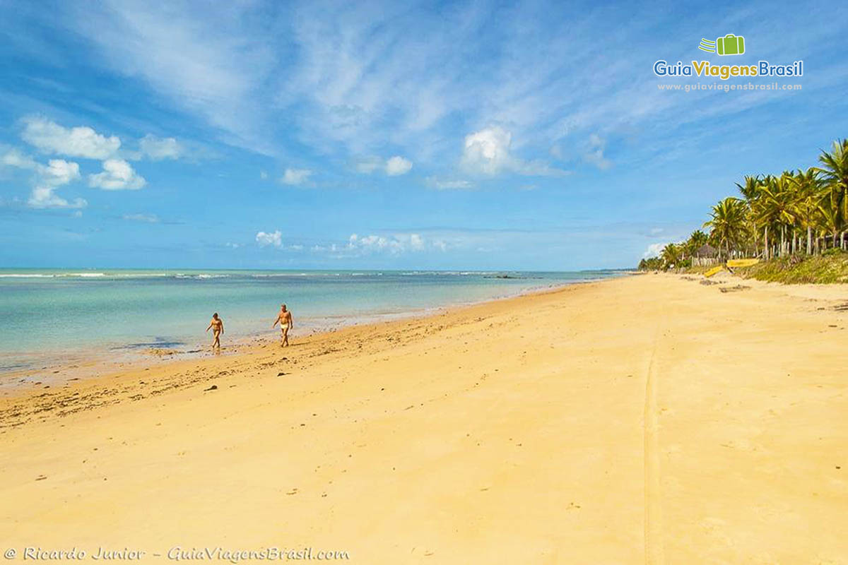 Imagem de casal caminhando na beira do mar.