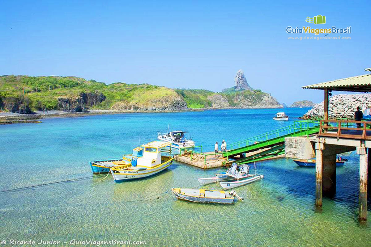 Imagem de barcos parados no deck, impressionante como as águas são transparentes, em Porto de Santo Antônio, em Fernando de Noronha, Pernambuco, Brasil.