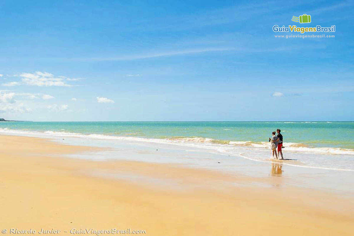 Imagem de pessoas caminhando na praia.