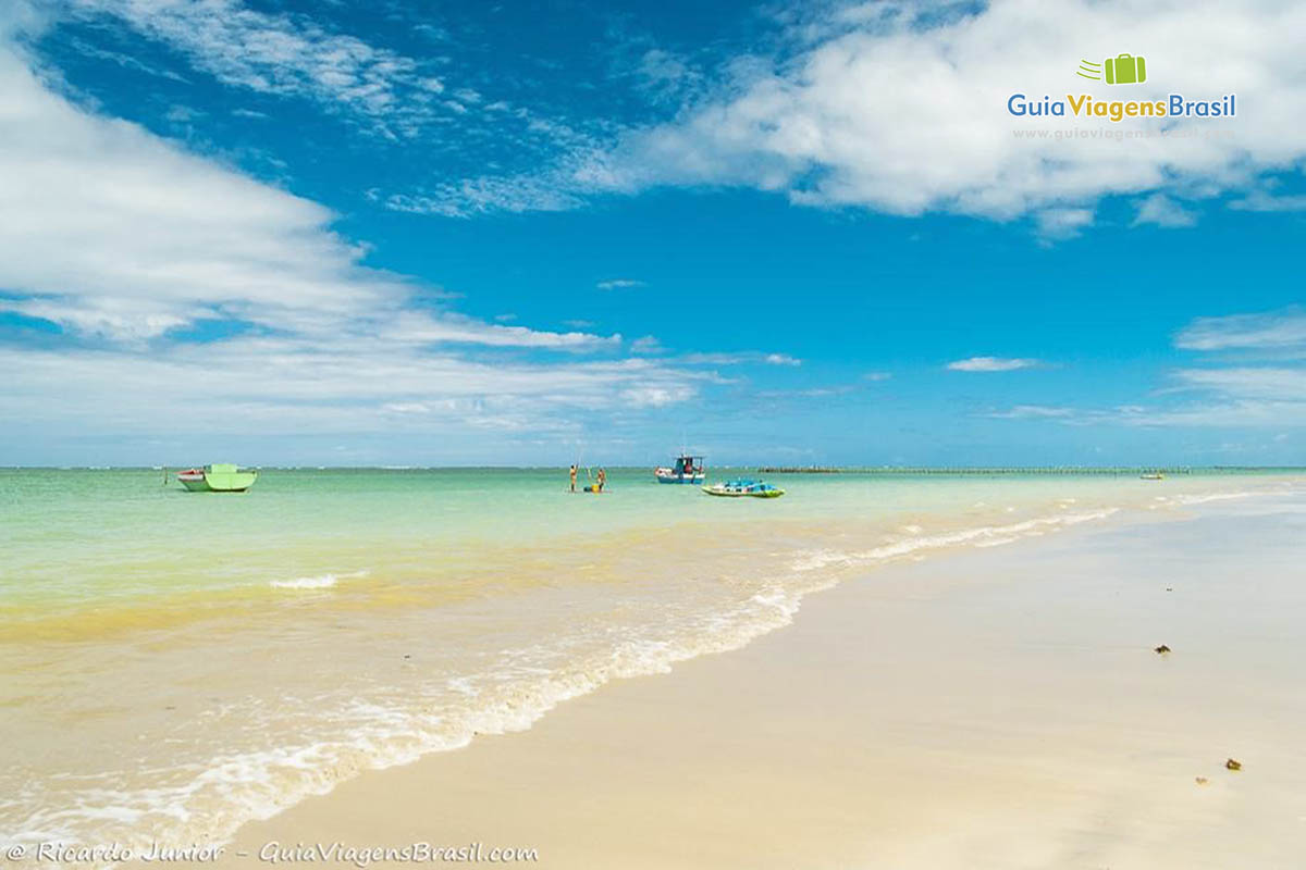 Imagem de barco de pescadores nas águas verdes da Praia do Toque. 