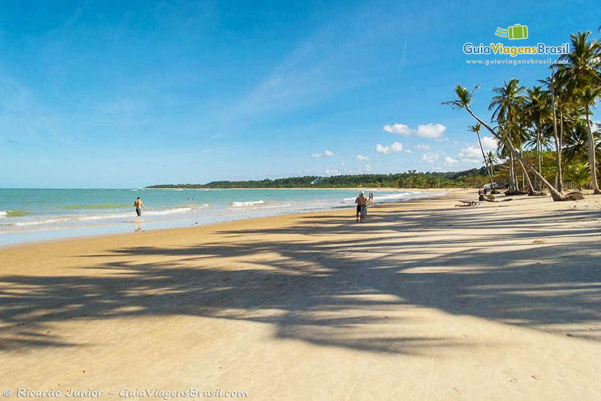 Imagem de turistas caminhando na Praia dos Coqueiros.