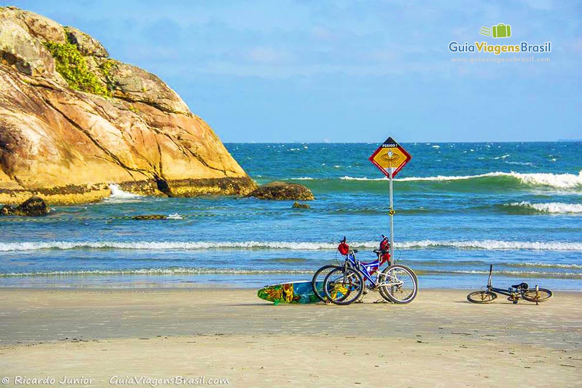 Imagem de bicicletas e prancha na areia da Praia Grande, na Ilha do Mel, Paraná, Brasil.