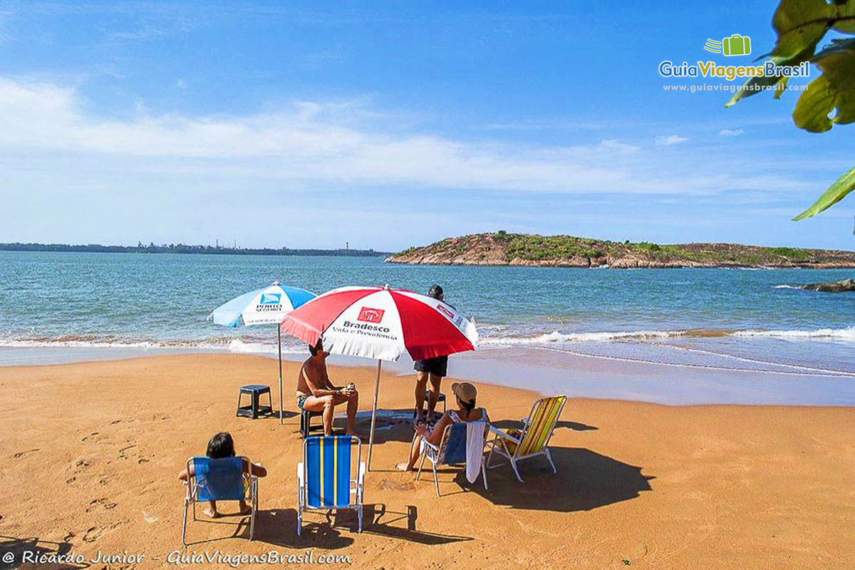 Imagem de turistas com seu guarda sol na Praia Ilha do Boi, em Vitória.
