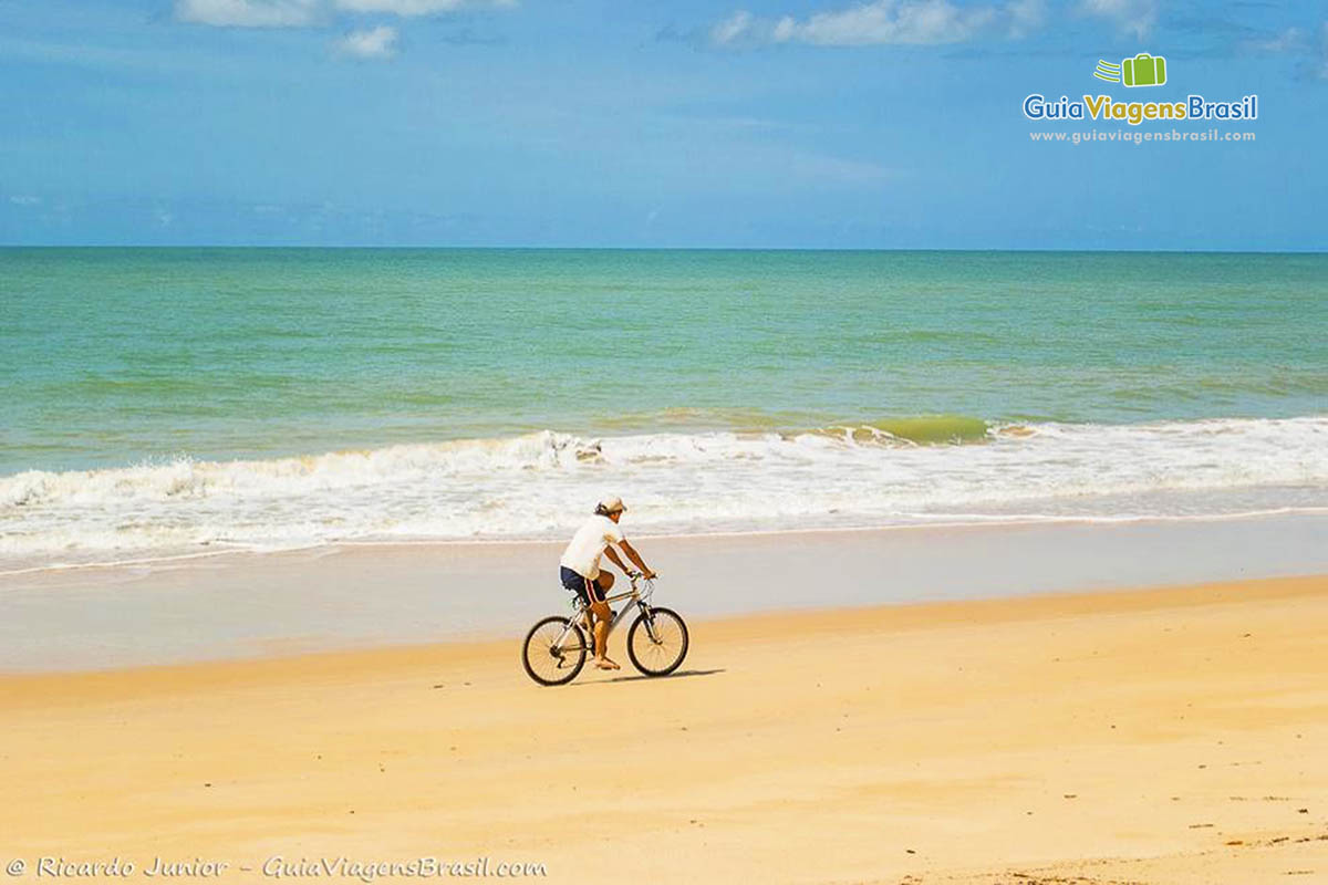 Imagem de pessoa andando de bicicleta na praia.