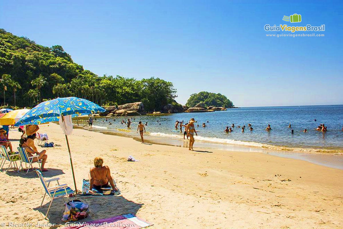 Imagem de turistas aproveitando um dia ensolarado na Praia Mansa, em Caiobá, Santa Catarina, Brasil.