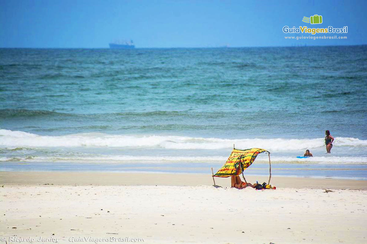 Imagem de uma cabana feita por turista, utilizando uma canga, na Praia Mar de Fora das Encantadas, na Ilha do Mel, Paraná, Brasil.
