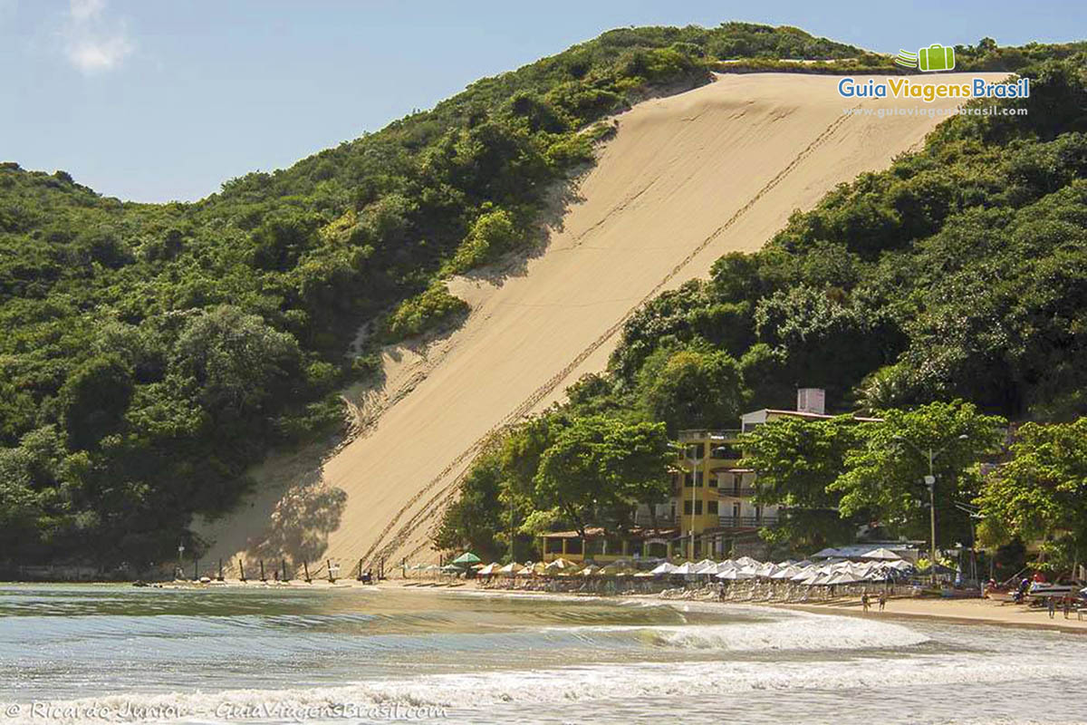 Imagem das dunas desembocando nas águas da Praia de Ponta Negra. 
