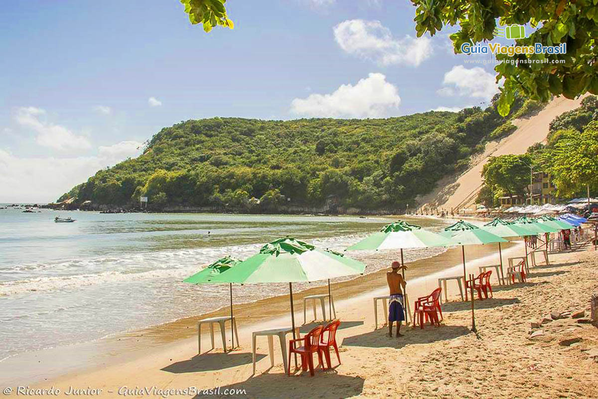 Imagem de guarda sol disposto na areia a espera de turistas.