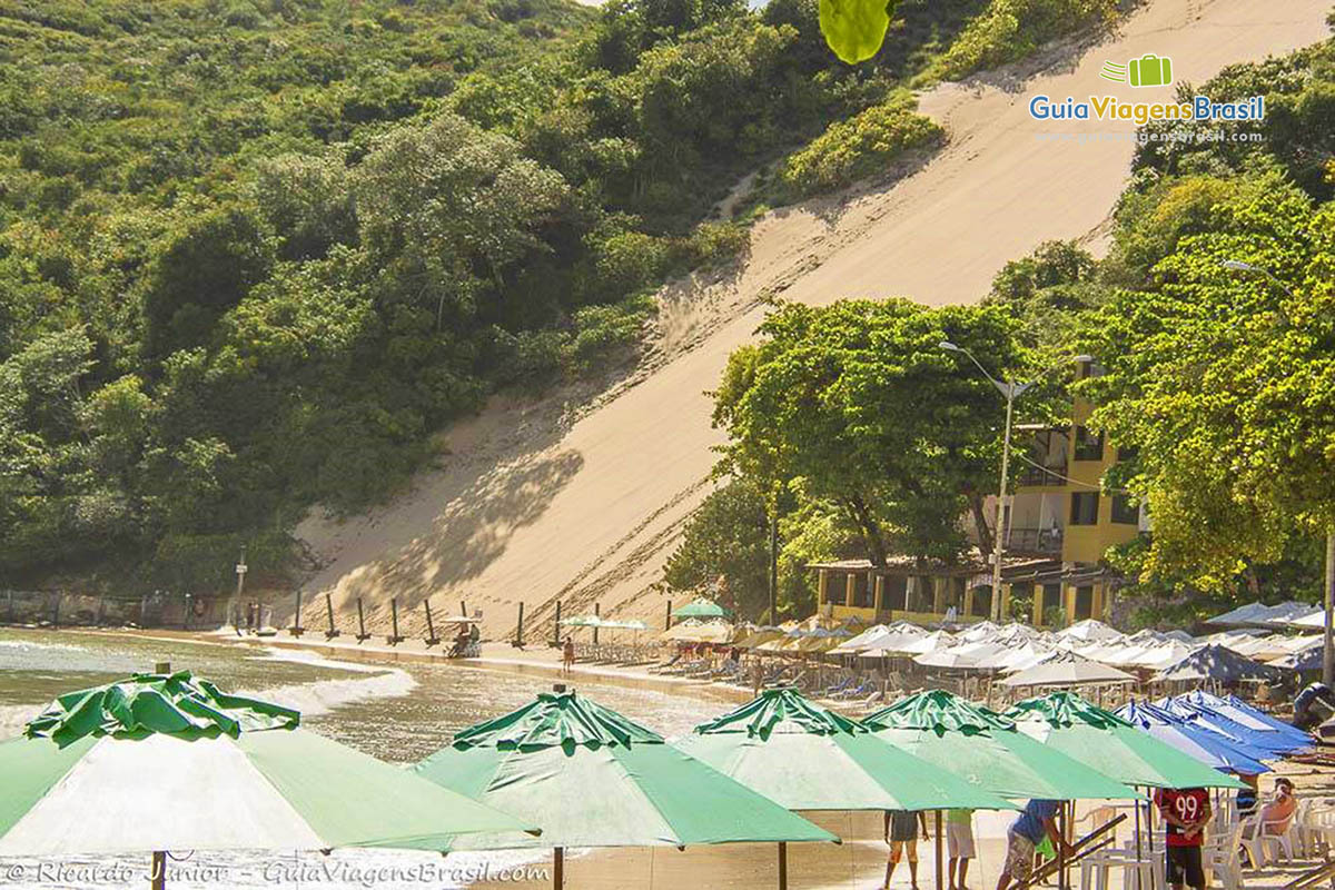 Imagem da ponta de guarda sol e a cima as dunas.