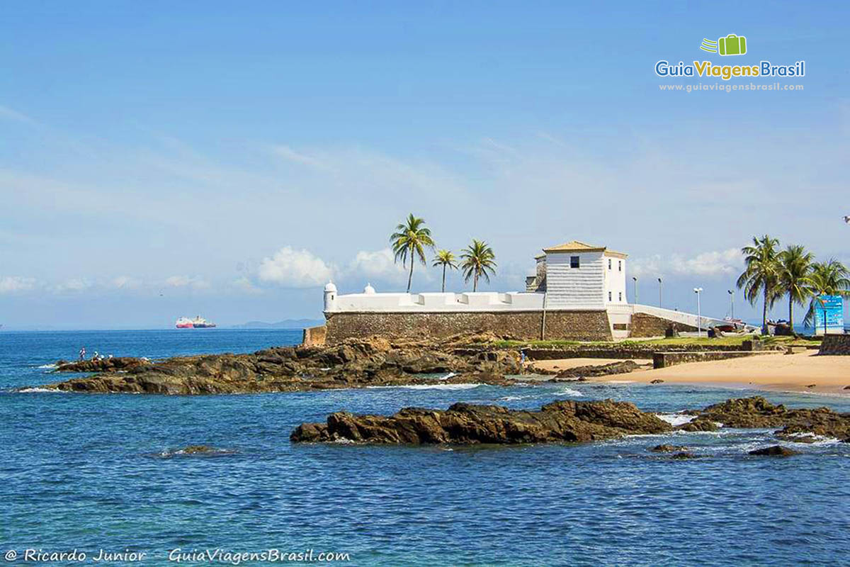 Imagem das águas azuis e ao fundo o Forte da Praia Porto da Barra.